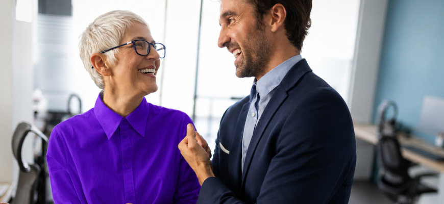 two people in an office talking and smiling